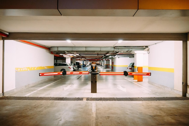 Foto entrada con barrera a un gran estacionamiento subterráneo con autos estacionados