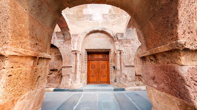 Entrada central arqueada no mosteiro Odzun com bivalve de madeira a porta de entrada coberta esculpida