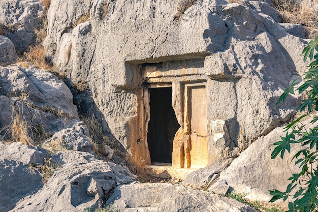 Entrada oscura misteriosa a una tumba de roca antigua, tallada en la ladera de la montaña