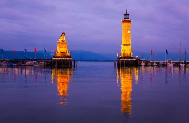 Entrada del puerto en el lago de Constanza. Vista del antiguo faro y la estatua del león en la entrada al puerto de Lindau en la puesta de sol