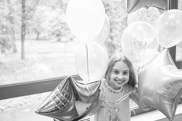 Entrando en el estado de ánimo de la fiesta Adorable niña pequeña disfrutando de su fiesta de cumpleaños Feliz linda niña celebrando su cumpleaños con globos de fiesta Fiesta como una estrella