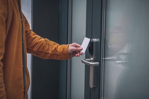 Entrar en el centro de negocios. Joven barbudo abriendo la puerta con una tarjeta de acceso