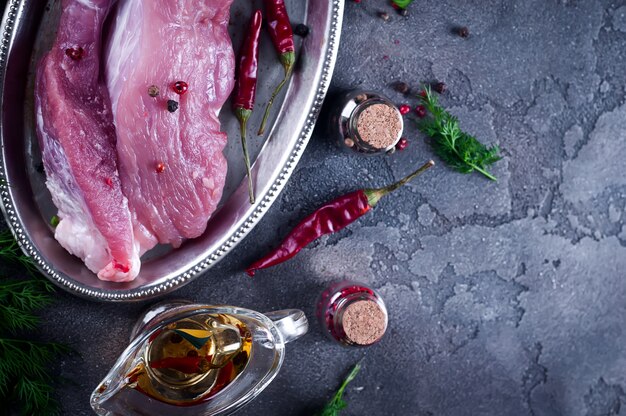 Entrecosto de bife de carne fresca crua e temperos na chapa de ferro com óleo, pimenta