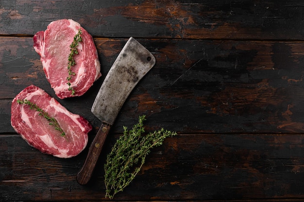 Entrecosto de bife de Ribeye de carne fresca crua do conjunto Black Angus, sobre fundo de mesa de madeira escura velha, vista superior plana, com espaço de cópia para texto