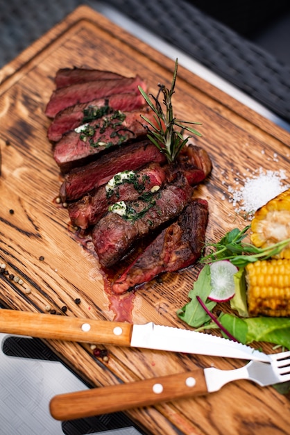 Entrecote Rindfleisch gegrilltes BBQ Steak Fleisch mit Rosmarinzweig und gegrilltem Gemüse Mais auf Holz