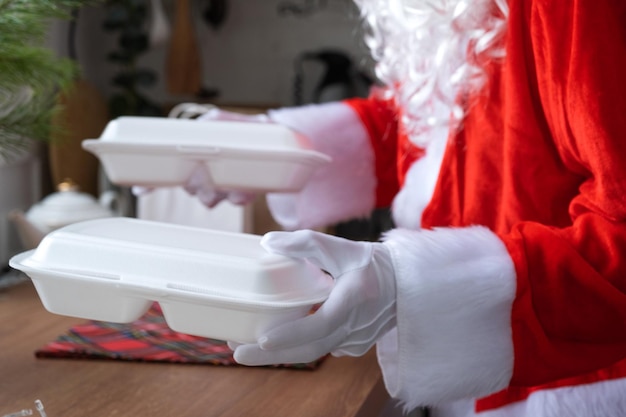 La entrega de alimentos a los contenedores de servicio a domicilio en manos de Santa Claus lo pone en la mesa de la cocina y se lo lleva Pedido caliente preparado Navidad Año nuevo vacaciones catering