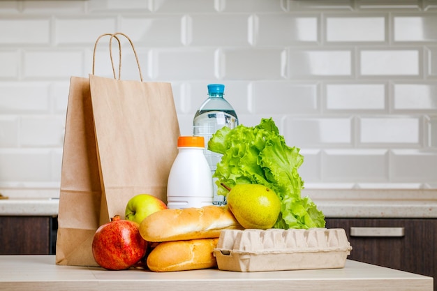 Entrega ao domicílio segura Uma caixa com vários produtos como leite, fruta e pão na cozinha