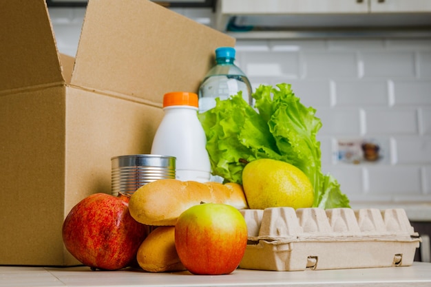 Entrega ao domicílio segura Uma caixa com vários produtos como leite, fruta e pão na cozinha
