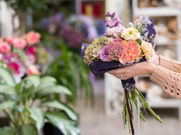 Entrega atempada de bouquet de flores para um dia especial - aniversário ou aniversário. Mãos de mulheres segurando um arranjo criativo de rosas, peônias, hortênsias e lilases