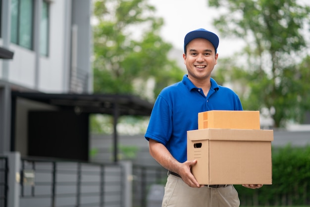 Entrega azul hombre asiático con paquete de caja de cartón