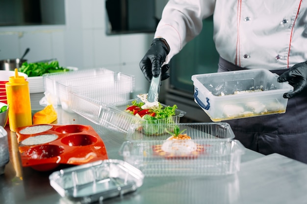 Entrega de comida en el restaurante. El chef prepara la comida en el restaurante y la empaca en platos desechables.