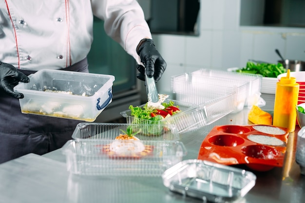 Entrega de comida en el restaurante. El chef prepara la comida en el restaurante y la empaqueta en platos desechables.