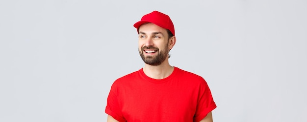 Entrega de compras en línea durante el concepto de cuarentena y comida para llevar chico alegre con barba en uniforme rojo ...