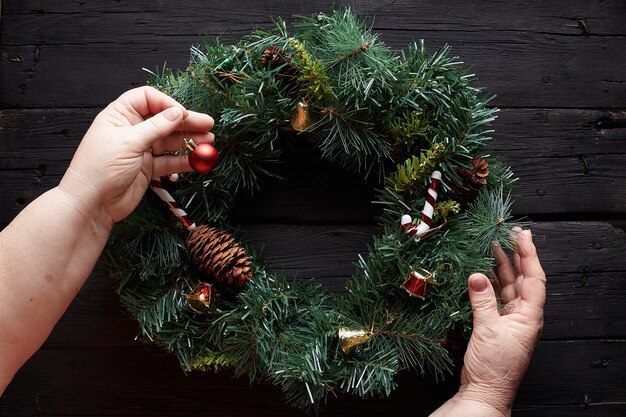 Entrega corona de Navidad sobre fondo de madera