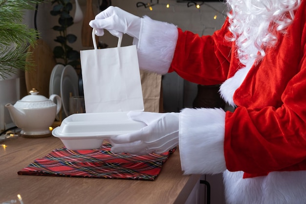 Entrega de comida em recipientes de serviço doméstico nas mãos do Papai Noel coloca na mesa da cozinha e leva embora Pedido quente pronto Natal Catering para feriados de ano novo