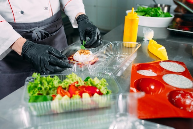 Entrega de comida no restaurante. o chef prepara a comida no restaurante e embala em pratos descartáveis.