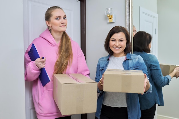 Entrega de mercadorias duas mulheres com caixas de papelão perto da porta da frente da casa