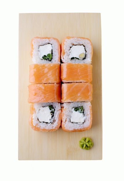 Entrega de restaurante de comida japonesa, conjunto de sushi. Rolos de sushi com salmão, cebola verde e queijo isolado na placa de madeira. vista do topo