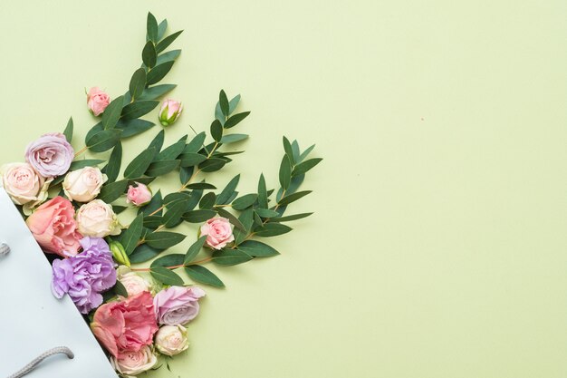 Entrega de flores frescas y follaje. Copie el espacio sobre fondo verde. Endecha plana.