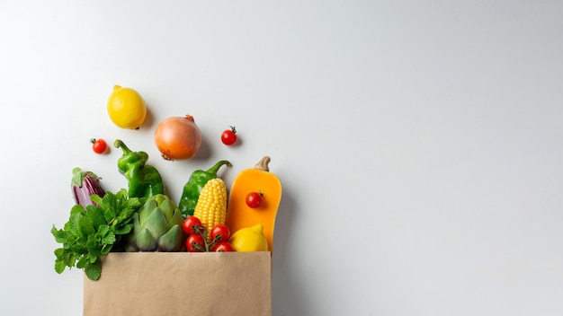 Entrega fondo de comida sana. Comida vegetariana vegana saludable en verduras y frutas de bolsa de papel en blanco, espacio de copia, banner. Supermercado de alimentos de compras y concepto de alimentación vegana limpia.