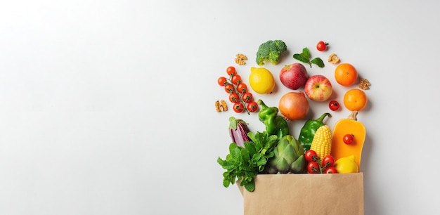 Entrega fondo de comida sana. Comida vegetariana vegana saludable en verduras y frutas de bolsa de papel en blanco, espacio de copia, banner. Supermercado de alimentos de compras y concepto de alimentación vegana limpia.