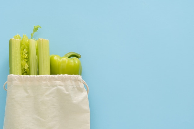 Entrega fondo de comida sana. Comida vegetariana vegana en verduras de bolsa de algodón ecológico sobre fondo azul. Supermercado de alimentos de compras de abarrotes y concepto de alimentación limpia.
