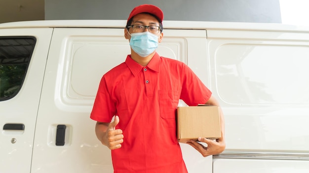 Entrega de joven asiático en uniforme rojo con paquetes y expresión OK