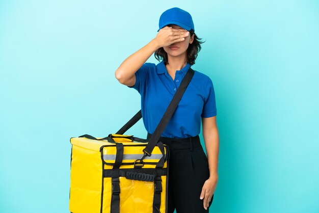 Entrega joven mujer con mochila térmica que cubre los ojos con las manos. No quiero ver algo