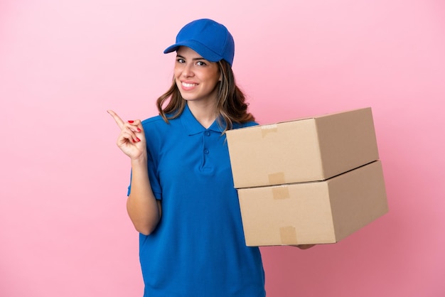 Entrega mujer italiana aislada sobre fondo rosa apuntando hacia un lado para presentar un producto