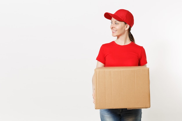 Entrega mujer sonriente en uniforme rojo aislado sobre fondo blanco. Mujer con gorra, camiseta, jeans trabajando como mensajero o distribuidor con caja de cartón. Recibiendo paquete. Copie el espacio para publicidad.