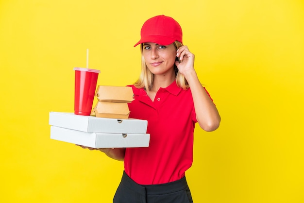 Foto entrega mujer uruguaya sosteniendo comida rápida aislada sobre fondo amarillo con dudas