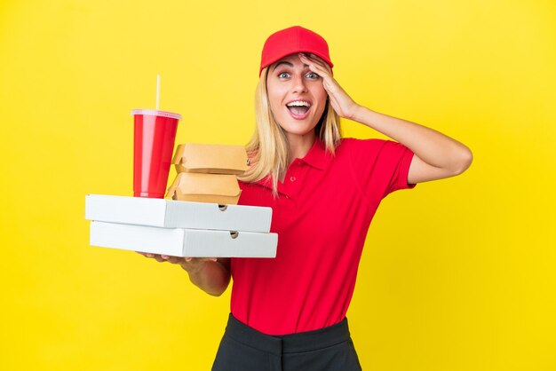 Entrega mujer uruguaya sosteniendo comida rápida aislada sobre fondo amarillo con expresión de sorpresa