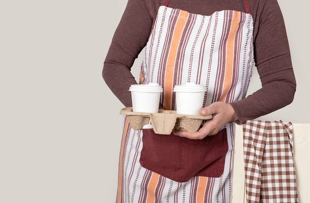 Entrega o Barista que sostiene el recipiente para llevar con dos tazas blancas de café.