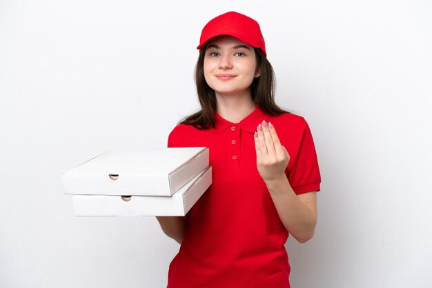 Entrega de pizza rusa joven recogiendo cajas de pizza aisladas en fondo blanco invitando a venir con la mano Feliz de que hayas venido