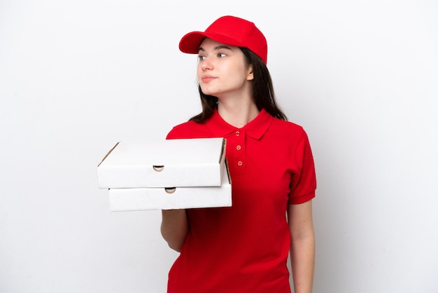 Entrega de pizza rusa joven recogiendo cajas de pizza aisladas en fondo blanco mirando hacia un lado