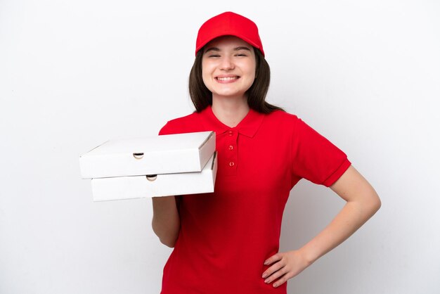 Entrega de pizza rusa joven recogiendo cajas de pizza aisladas sobre fondo blanco posando con los brazos en la cadera y sonriendo