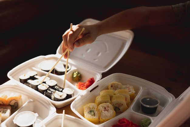 Entrega de rollos de sushi en recipientes de plástico para alimentos Cocina japonesa Juego de rollos de sushi en recipientes desechables Servicio de entrega de alimentos y concepto de comida para llevar