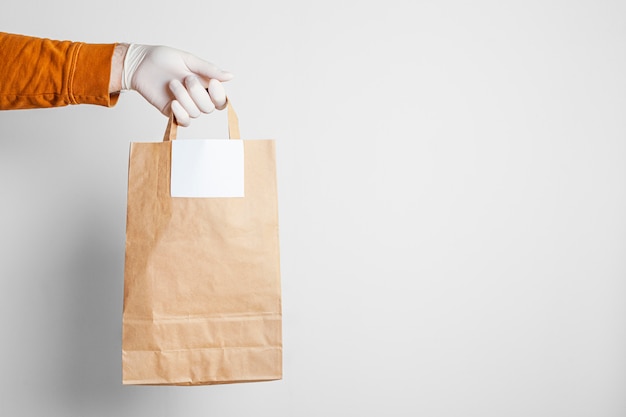 Entrega segura de alimentos em um saco de artesanato e entregador de pizza em casa, sobre um fundo branco