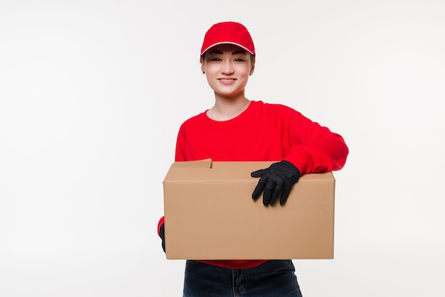 Entrega servicio postal mujer asiática sosteniendo y entregando el paquete con gorra roja