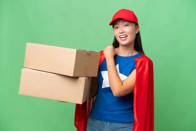 Entrega de superhéroe Mujer asiática sosteniendo cajas sobre un fondo aislado celebrando una victoria