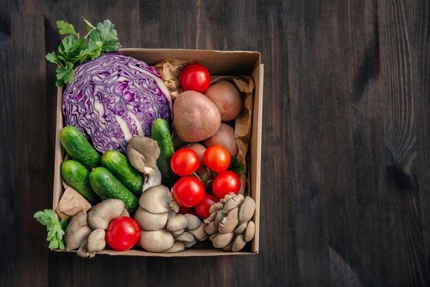 Entrega de verduras frescas en una caja de papel. Vista superior de comida vegetariana saludable sobre fondo de madera