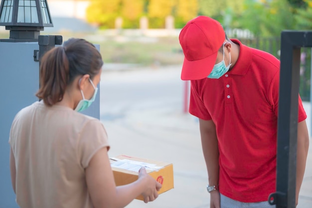 Entregador asiático usa máscara protetora em uniforme vermelho Conceito de entrega de alimentos e produtos onlineNovo normal em covid19