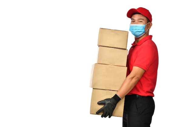 Entregador asiático usando máscara facial e luvas em uniforme vermelho entregando caixa de pacote isolada no branco durante surto de COVID-19