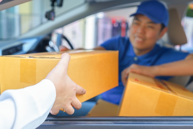 Entregador, dando uma caixa do pacote para o cliente enquanto está sentado no carro