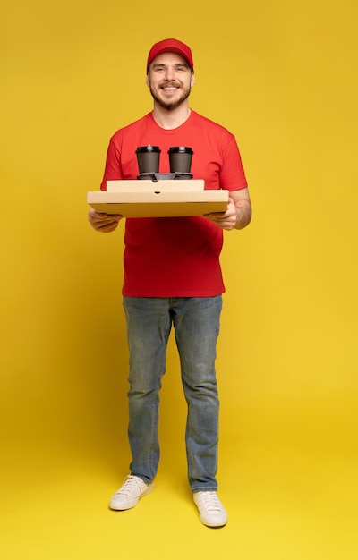 Foto entregador de boné vermelho, uniforme de camiseta isolado na parede amarela