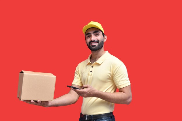 entregador de camiseta amarela usando celphone e segurando uma caixa de embalagem modelo indiano do paquistanês