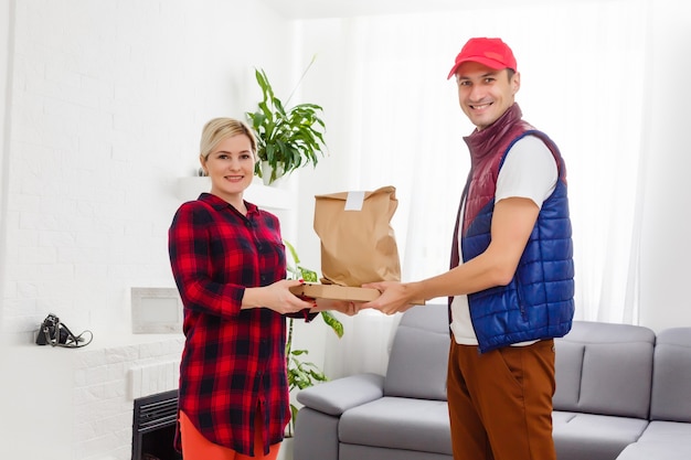 Entregador de comida segurando sacola de papel em um apartamento