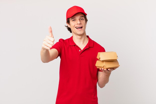 Entregador de hambúrguer orgulhoso, sorrindo positivamente com o polegar para cima