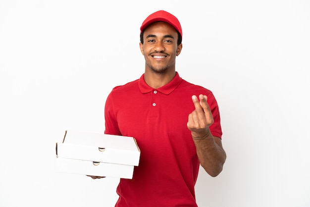 Entregador de pizza afro-americano pegando caixas de pizza na parede branca isolada fazendo gesto de dinheiro