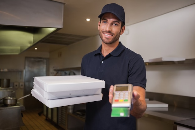 Entregador de pizza alegre segurando a máquina de cartão de crédito